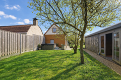 Zonnige tuin met houten schuur.png